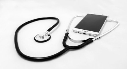 Medical stethoscope tool over the surface of a mobile smart phone, composition isolated over the white background. with Selective Focus