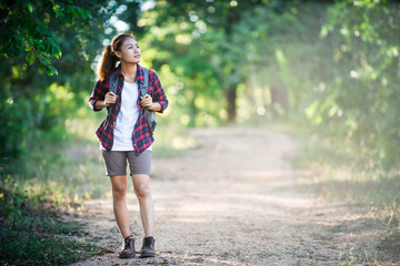 Young woman hiker with backpack walking and smiling on a country