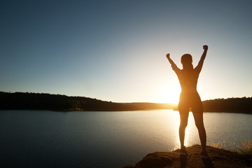 Silhouette of woman achieve hiking on peak with lake view sunset