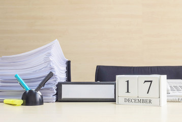 Closeup white wooden calendar with black 17 december word on blurred brown wood desk and wood wall textured background in office room view with copy space , selective focus at the calendar