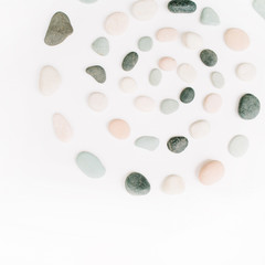 Creative spiral arrangement of colored stones. Mint, pink, beige and grey stones on white. Flat lay, top view