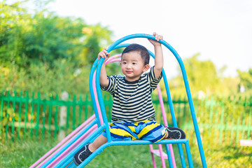 Little Asian kid playing slide at the playground