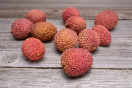 Lychee, Fresh lychee and peeled showing the red skin and white flesh with green leaf on a wooden background