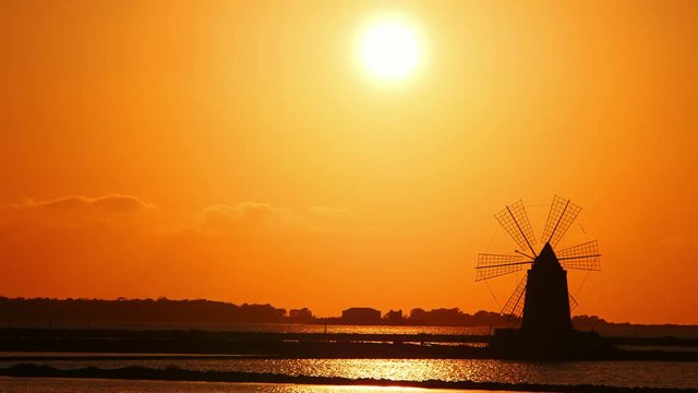windmill at sunset: sky, sun, yellow, salt pans of Trapani, Sicily, Italy