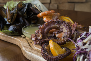 Seafood set with octopus, shrimps and shells on a wooden platter.