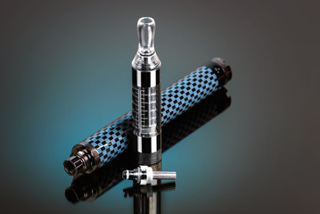 Vape, electronic cigarette exploded next to a conventional cigarette on a dark background with a...