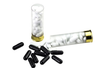 Concept of medical pills side effects. Transparent plastic Shotgun 12 caliber shells full of white vitamin pills. Several white pills outside the shell. Near white pills are black drugs. Isolated.