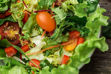 Salad with fresh vegetables - tomatoes, carrots, bell peppers and mixed greens - arugula, mesclun, mache.