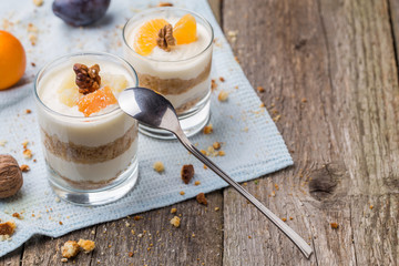 Fresh homemade dessert with biscuits, yogurt, tangerines and walnuts, served in a glass