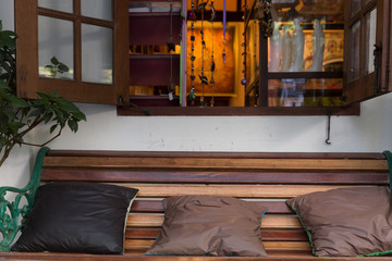 Obraz na płótnie Canvas brown pillow on wood bench beside opening window