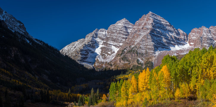 The morning sun lights up the aspens at the base of Maroon Bells