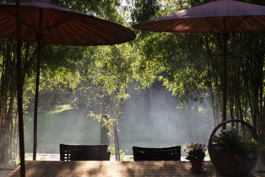 Table And Chair And Red Umbrella At Patio With Light Ray Through