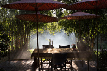 Fototapeta premium table and chair and red umbrella at patio with light ray through