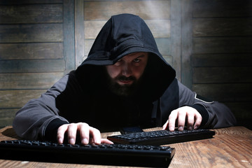 hacker in the black hood in a room with wooden walls