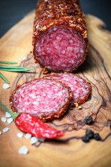 dried salami crusted in ground red pepper on dark background