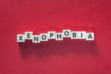 Xenophobia word written with blocks on red background. Social issues concept