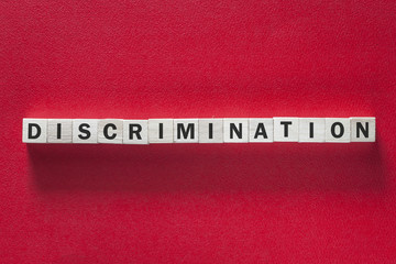 Discrimination word written with blocks on red background. Social issues concept