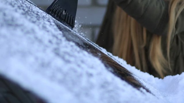 Woman scraping the frost from car windshield