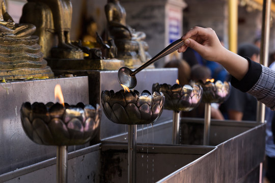 people pour oil to light candle in oil lantern at buddhist templ