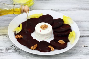 Pouring oil on carpaccio from red beetroot & goat cheese