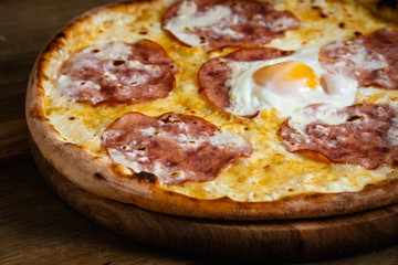 Pizza with ham and egg on wood background