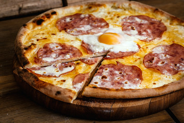 Pizza with ham and egg on wood background