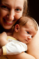 Young mother holding her baby boy and smiling at the camera. Iso
