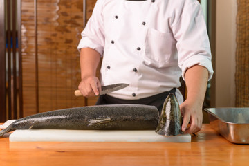 Japanese Chef preparing a fresh salmon on a cutting board 