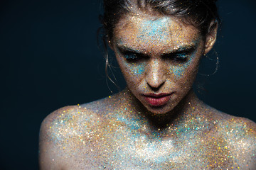Beauty portrait of young woman with sparkles on her face