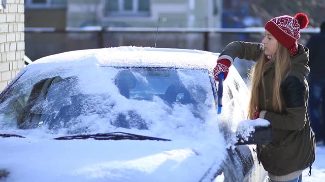 Woman cleaning snow from car roof using brush