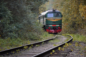 Naklejka premium Stary pociąg jadący po torach w środku jesiennego lasu.