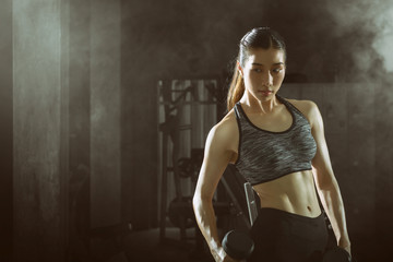 Fototapeta na wymiar Toned picture,Asian fitness girl with perfect shape body workout lifting a dumbbell.