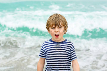 little kid boy running on the beach of ocean