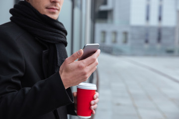 Cropped image of business man with coffee and phone outdoors