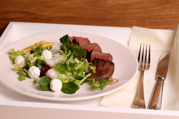 Medium rare steak with salad on a white plate, homemade food. rustic food.