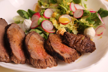 Medium rare steak with salad on a white plate, homemade food. rustic food.