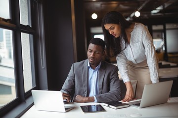 Businessman and a colleague working over laptop