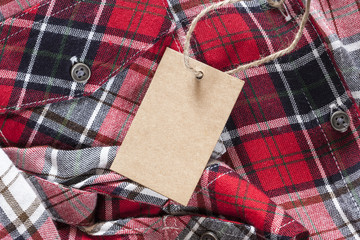 Blank tag made of recycled paper on clothes background