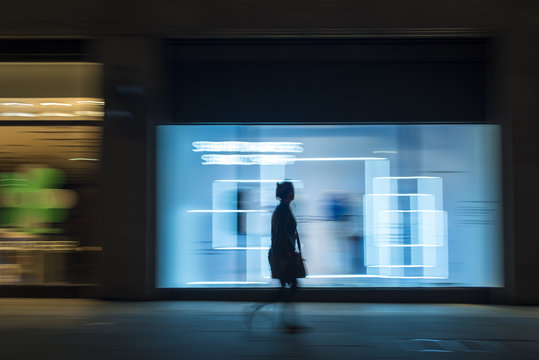 Pedestrian in a rush in the city walking at night on Oxford Street, London