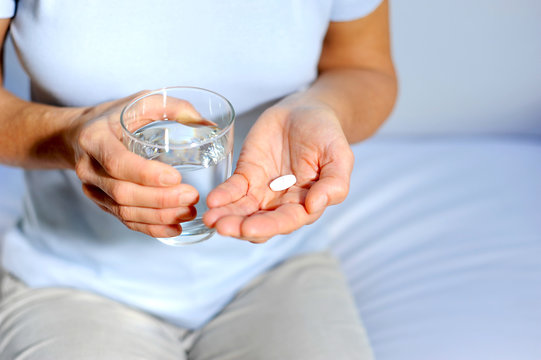 Frau nimmt Tablette gegen Schmerzen mit einem Glas Wasser ein