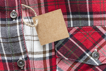 Blank tag made of recycled paper on clothes background