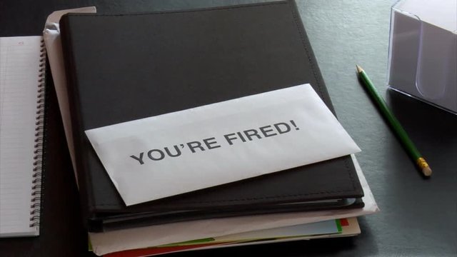 Getting a YOU'RE FIRED notice at office desk with undone paperwork