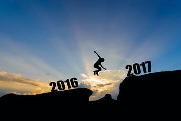 Fototapeta na wymiar man jump between 2016 and 2017 years on sunset background.