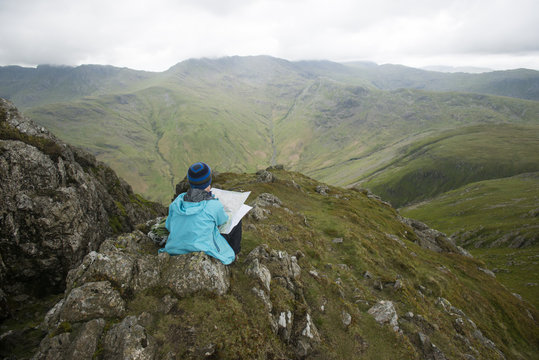 A woman stops near Stickle Pike in The Lake District to check her bearings on a map, Cumbria