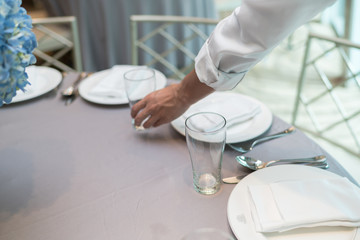 Waiter hand place dishes on the table, meal preparation
