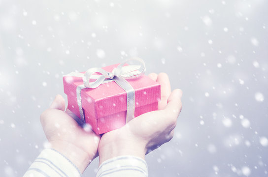 Closeup, Hand holding red gift box and snow in winter, New year holidays and greeting season concept