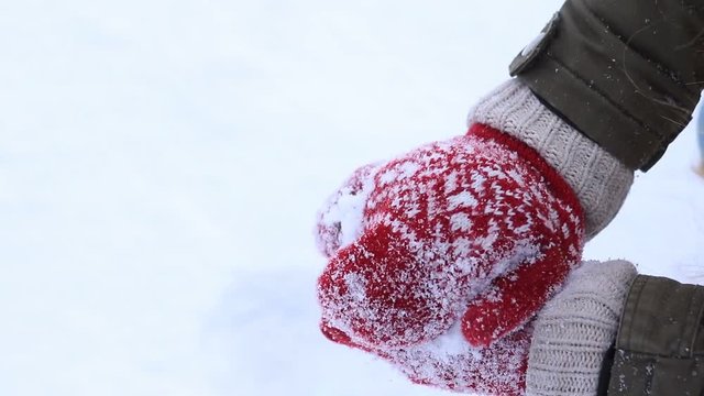 Female hands in knitted mittens making snowball