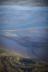 aerial view of the mudflat coastline at low tide with water winding in the mud and sand bank, Frisian island Ameland, The Netherlands