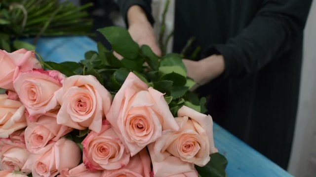 Close-up of female hands preparing a rose flower bouquet at  flower shop