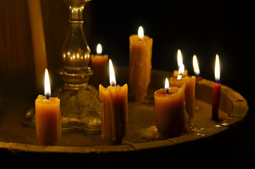 Antique candle burning  in a dark room. Christmas Eve, divination, yuletide. Christmas backgrounds. holiday rituals, religion, spirituality, zen. space for text, close-up, copy space.